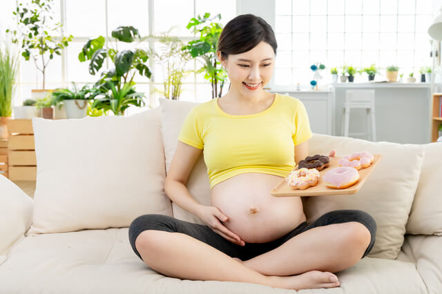 ドーナツを食べる妊婦