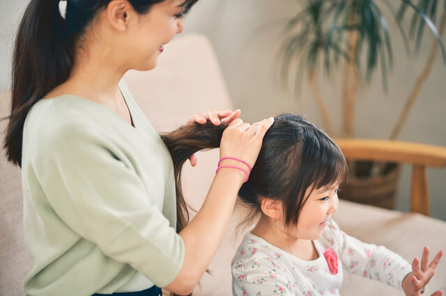 子供の髪を結ぶママ
