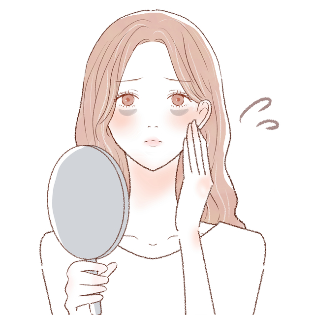 目の下のくすみを鏡で見る女性