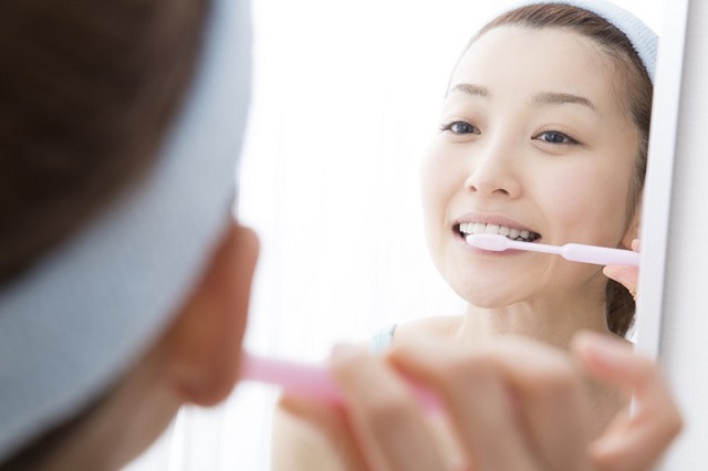 鏡を見ながら歯を磨く女性